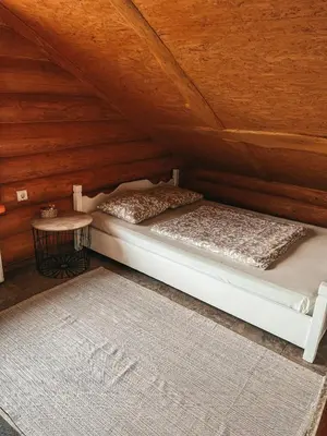 a bed in a attic with a table and a rug at Laukupės sodyba in Rokiškis