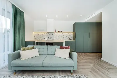 a living room with a blue couch and a kitchen at Cozy Piliamiesčio apartament No 1 by URBAN RENT in Kaunas