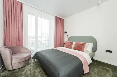 a bedroom with a bed and a chair and a window at Cozy Piliamiesčio apartament No 1 by URBAN RENT in Kaunas