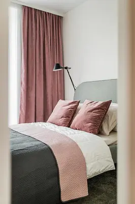 a bedroom with a bed with pink pillows and a lamp at Cozy Piliamiesčio apartament No 1 by URBAN RENT in Kaunas