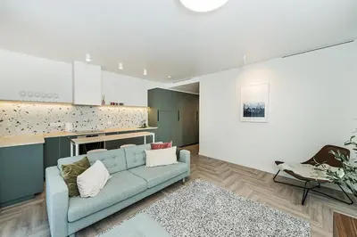 a living room with a blue couch and a kitchen at Cozy Piliamiesčio apartament No 1 by URBAN RENT in Kaunas