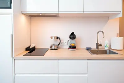 a kitchen with white cabinets and a sink at Crown Apartment in Ukmergė