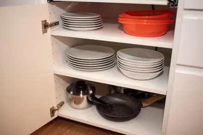 a cupboard filled with plates and bowls and pans at Crown Apartment in Ukmergė