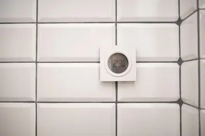 a light switch on a white tiled wall at Crown Apartment in Ukmergė