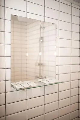 a mirror on a white tiled wall with a shower at Crown Apartment in Ukmergė