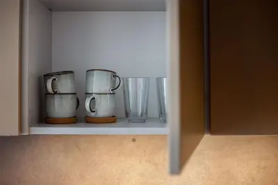 a shelf with cups and vases on it at #stayhere Modern & Compact 1BDR Uptown Vilnius in Vilnius