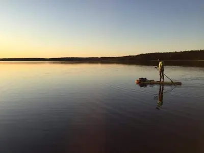 a man standing on a paddle board in a lake at ForrestVila in Karačiūnai