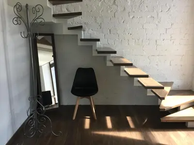 a black chair sitting next to a staircase with a mirror at Loft 65 Panoramic View in Vilnius