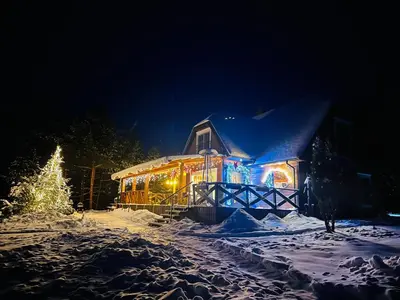 a house covered in lights in the snow at night at Sodyba Ciciriai in Vėdariai