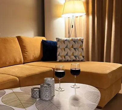 two glasses of wine on a table in front of a couch at Blue Peony in Druskininkai