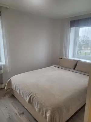 a bed in a white room with a window at Maironio Apartamentai in Radviliškis
