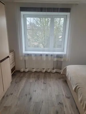 a bedroom with a large window and a wooden floor at Maironio Apartamentai in Radviliškis