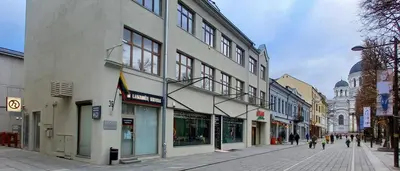 a street with buildings and people walking down a street at Laisves Apartment Kaunas in Kaunas