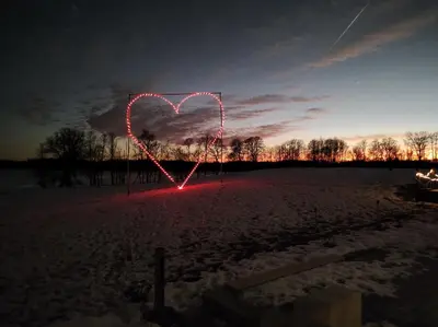 a heart sign is lit up in a field at night at Palaima Hotel Anykščiai in Anykščiai