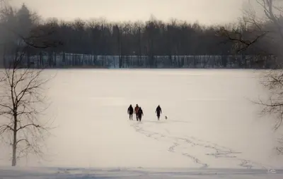 three people are walking across a snow covered field at Palaima Hotel Anykščiai in Anykščiai