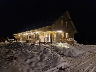 a house with lights in the snow at night at Palaima Hotel Anykščiai in Anykščiai
