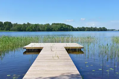 a wooden dock in the middle of a lake at Palaima Hotel Anykščiai in Anykščiai