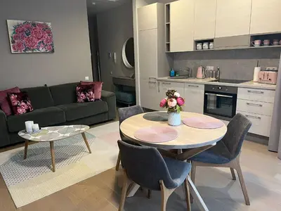 a kitchen and a living room with a table and chairs at Pink Peony in Druskininkai