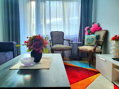 a living room with a table with a vase of flowers at Lovely 2-bedroom Flat in Šiauliai in Šiauliai