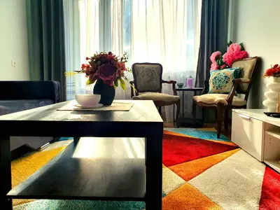 a living room with a table and a colorful rug at Lovely 2-bedroom Flat in Šiauliai in Šiauliai