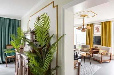 a living room with a palm plant in the foreground at Entire interwar Villa Grabyte by pine forest on the bank of the river- 8min by car from old town in Kaunas