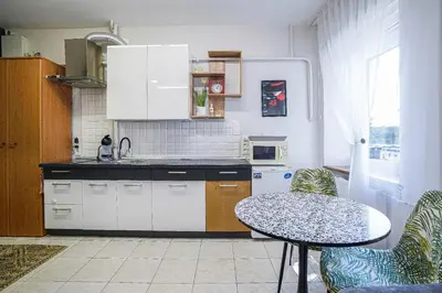 a kitchen with white cabinets and a table and chairs at Jaukus ir kokybiškas butas Panevėžio centre in Panevėžys