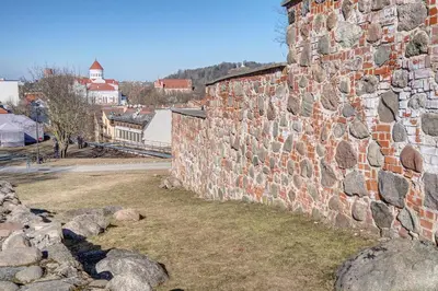 a large brick wall with rocks in front of a city at Mini apartament by Town hall, self chek-in in Vilnius