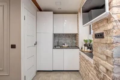a kitchen with white cabinets and a stone wall at Mini apartament by Town hall, self chek-in in Vilnius