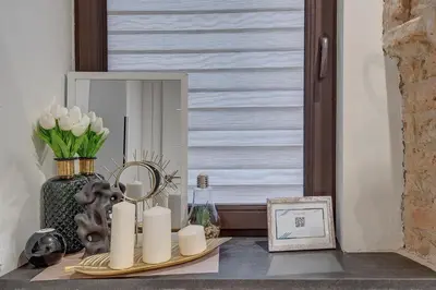 a table with candles and a mirror and a vase with flowers at Mini apartament by Town hall, self chek-in in Vilnius