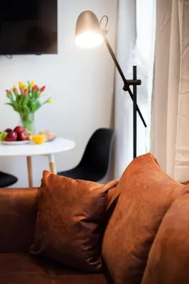 a lamp sitting next to a couch with a pillow at #stayhere - Modern & Central Studio Apartments in Vilnius