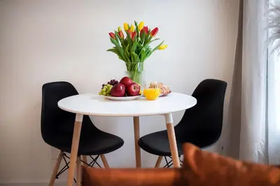 a table with a bowl of fruit and a vase of flowers at #stayhere - Modern & Central Studio Apartments in Vilnius