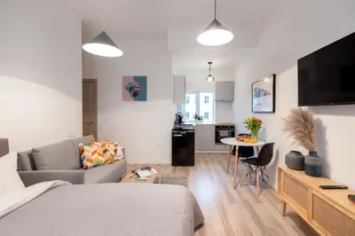 a living room with a bed and a kitchen with a table at #stayhere - Modern & Central Studio Apartments in Vilnius