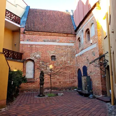 a large brick building with a statue in the courtyard at ReHouse Stikliu 4 in Vilnius