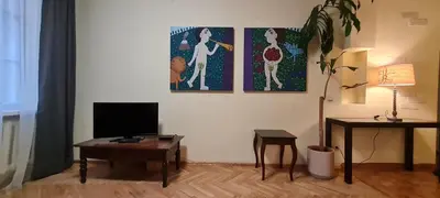 a living room with a tv and a table and paintings at ReHouse Stikliu 4 in Vilnius