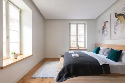 a bedroom with a large bed and two windows at Pilies Street Exclusive Apartment by Reside Baltic in Vilnius