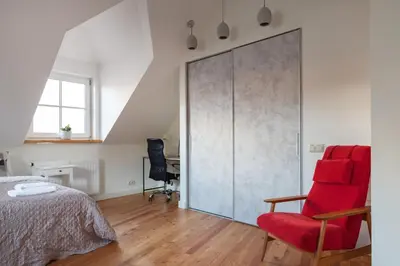 a bedroom with a red chair and a large sliding door at Pilies Street Exclusive Apartment by Reside Baltic in Vilnius
