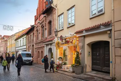 a group of people walking down a street with buildings at Pilies Street Exclusive Apartment by Reside Baltic in Vilnius
