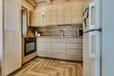 a kitchen with wooden cabinets and a wooden floor at Kaimo turizmo sodyba „Šerno slėnis“ in Vėdariai