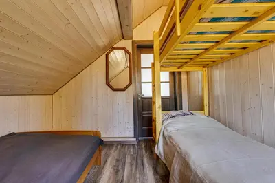 two beds in a small room with wooden walls at Kaimo turizmo sodyba „Šerno slėnis“ in Vėdariai