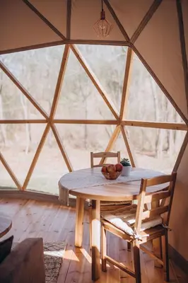 a table and chairs in a yurt with a window at VasaRojaus Kupolai in Birštonas