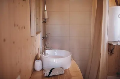 a bathroom with a white sink on a wooden counter at VasaRojaus Kupolai in Birštonas