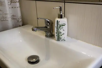 a bathroom sink with a soap dispenser on it at Cozy apartment in Jeruzalė in Vilnius