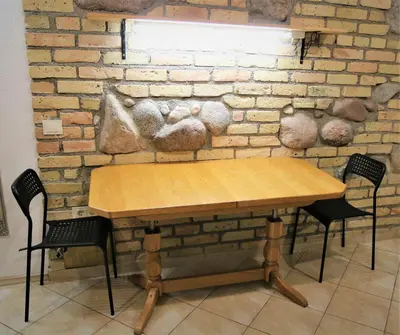 a wooden table and chairs against a brick wall at Cozy apartment in Jeruzalė in Vilnius