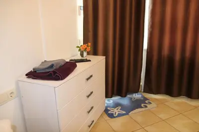 a dresser with a vase of flowers on top of it at Cozy apartment in Jeruzalė in Vilnius