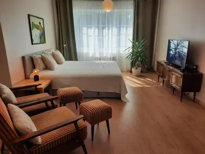 a bedroom with a bed and a tv and a couch at Šeimos Būstas Homestay in Šiauliai