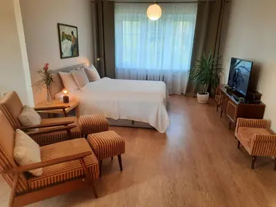 a bedroom with a white bed and a tv and chairs at Šeimos Būstas Homestay in Šiauliai