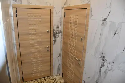 two wooden doors in a bathroom with marble walls at Familia Apartments in Vilnius