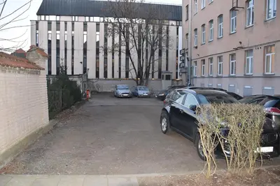 a parking lot with cars parked in front of a building at Familia Apartments in Vilnius
