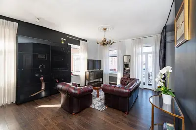 a living room with leather furniture and a chandelier at Retro Studio Old Town Apartment by Domvia in Kaunas