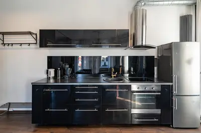 a kitchen with black cabinets and a stainless steel refrigerator at Retro Studio Old Town Apartment by Domvia in Kaunas